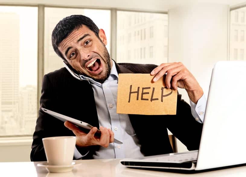 Business-Fear-Computer-Help man holding up a help sign while on the phone